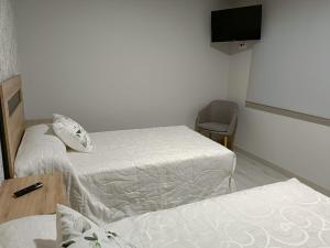 a small room with two beds and a television at O nido do cuco in Muxia