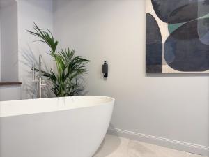a white bath tub in a bathroom with a plant at Maison Alsacienne 4Ch & Suite Parentale sur la Route des Vins in Marlenheim