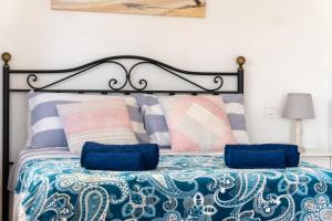 a bedroom with a bed with blue and pink pillows at El Rinconcito in Jávea