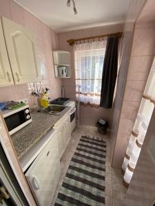 a small kitchen with white cabinets and a sink at Aranypatak Apartmanház Hévíz in Hévíz