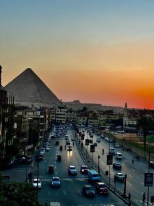 a city with a lot of cars on a road with a pyramid at Khufu Pyramids View Inn in Cairo +28 photos