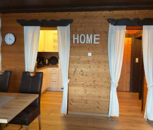 a kitchen with white curtains and a home sign on a wall at Ferienwohnung & Spa Renate in Sibratsgfäll