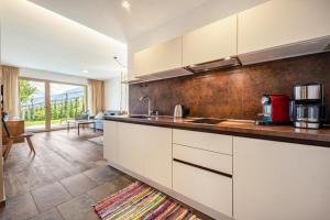 eine Küche mit weißen Schränken und ein Wohnzimmer in der Unterkunft Pataunerhof Betulla Quercus in Dorf Tirol