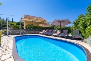 Una piscina con sillas y sombrillas al lado de una casa. en Three Bedroom Holiday Home with Pool, en Molunat 26 fotos más