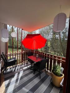 a red table and chairs on a balcony with a red umbrella at Schönhier - Design Apartment mit Pool, Sauna in Schluchsee