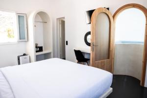 a bedroom with a white bed and a desk at White Cave Villas in Oia