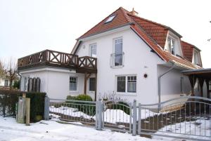 ein weißes Haus mit einem Holzzaun im Schnee in der Unterkunft Ostseesonne in Prerow