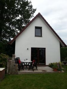 a white house with a table and chairs in the yard at Ferienhaus Utspannen in Prerow