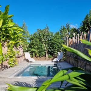 a swimming pool with two chairs and a fence at Ecolodge Sabba - Natural pool & beach in Saint-François