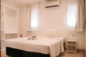 una camera bianca con un letto e un asciugamano sopra di Pipa Casas Blancas Residencial a Pipa Altre 53 foto