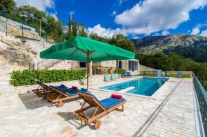 a pool with two chairs and a green umbrella at Breathtaking Scenic Villa with Pool in Dubravka