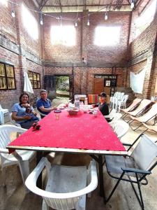a group of people sitting around a large red table at la casa de mamá in Huayopata