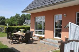 eine Terrasse mit einem Tisch und Stühlen sowie ein Haus in der Unterkunft Ferienhaus Uhlenhus in Prerow