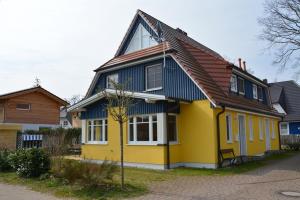 uma casa amarela e azul com um telhado castanho em Hagens Hus em Prerow
