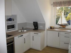 a kitchen with white cabinets and a sink and a window at Strandlust in Prerow