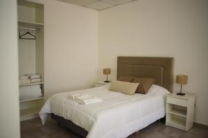 a bedroom with a large white bed with two lamps at Don Pedro Apart Hotel in Corrientes