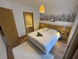 ein Schlafzimmer mit einem weißen Bett mit einem schwarzen Bild an der Wand in der Unterkunft Chalet de l'Olympe in Les Allues