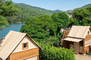 a couple of huts with a river in the background at Camping Lac de Villefort in Villefort +54 photos