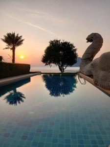 einen Pool mit Schwanenstatus neben einem Sonnenuntergang in der Unterkunft OMG !! Amazing Sea Views !! Stunning Sunsets !! Khao Thong Krabi Thailand in Ban Khao Thong