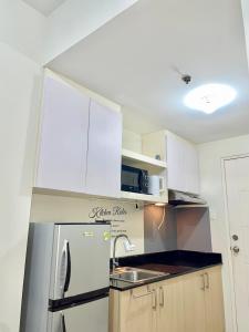 a kitchen with a stainless steel refrigerator and white cabinets at The Luna's at Wind Residences in Kaybagal