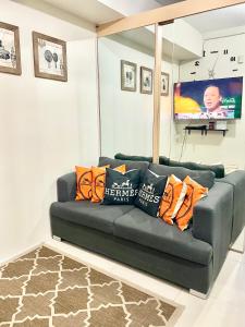 a living room with a black couch with orange pillows at The Luna's at Wind Residences in Kaybagal