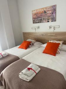 2 camas en una habitación con naranja y blanco en Quererte, en Teruel