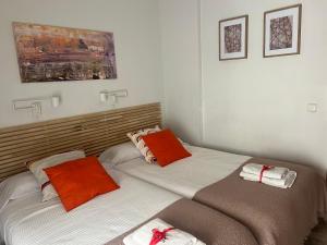 due letti in una camera da letto con cuscini arancioni e bianchi di Quererte a Teruel