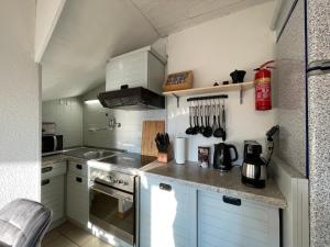 a small kitchen with white cabinets and a stove at Moselgarten Bullay Zentral Grün Direkt an der Mosel in Bullay +6 photos