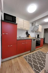 a kitchen with red cabinets and a microwave at FeWo Rehborn in Rehborn +9 photos