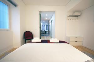 a bedroom with a large white bed and a red chair at 19inLisbon in Lisbon