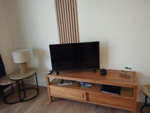 a flat screen tv sitting on top of a wooden entertainment center at Les Voiles Blanches in Le Crotoy