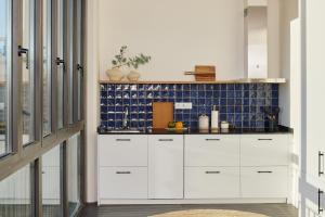 a kitchen with white cabinets and blue tiles at Factory Apartments Barcelona in Barcelona