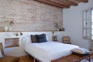 a bedroom with a white bed and a brick wall at Factory Apartments Barcelona in Barcelona