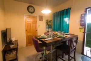 a dining room table with chairs and a clock on the wall at Casa Cicada Back Appartment in Chaguanas
