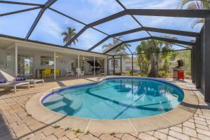 a swimming pool in a yard with a house at Gulf Access, Heated Pool, Dock, Lanai -Sunset Coast Bungalow - Roelens in Cape Coral