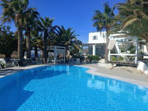 a swimming pool with palm trees and a building at Zephyros in Paraga