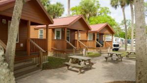 a row of wooden lodges with picnic tables in front of them at Road Runner Travel Resort in Fort Pierce