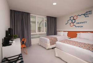 a hotel room with two beds and a tv at Novus Plaza Hodelpa in Santo Domingo