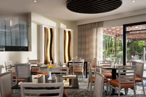 a dining room with tables and chairs and windows at Hodelpa Garden Court in Santiago de los Caballeros