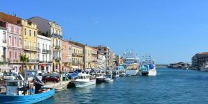 a group of boats docked in a canal with buildings at Appartement bord d'etang in Poussan +2 photos