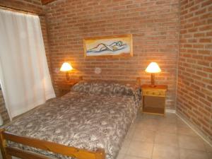 um quarto com uma cama, 2 candeeiros e uma parede de tijolos em Cabañas Tio Willy em Villa Carlos Paz