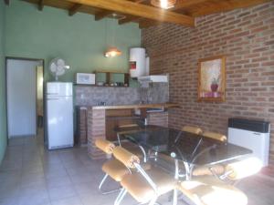 eine Küche mit einem Tisch, Stühlen und einer Ziegelwand in der Unterkunft Cabañas Tio Willy in Villa Carlos Paz