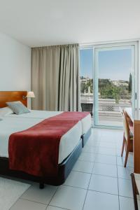 a hotel room with a bed and a large window at Hotel Sao Sebastiao de Boliqueime in Boliqueime