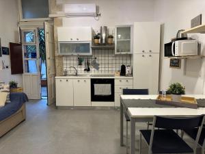 Una cocina con gabinetes blancos y una mesa con sillas. en Nesea Home, en Siracusa