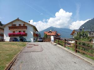 a person walking down a road next to a house at Casa Bezzi in Pellizzano