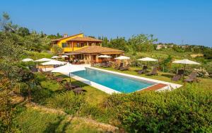 a swimming pool with umbrellas and a house at Villa Amadeo by PosarelliVillas in Montaione