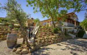 a house with a stone retaining wall and a tree at Villa Amadeo by PosarelliVillas in Montaione