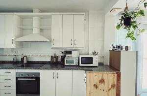 a white kitchen with white cabinets and appliances at Casa La Higuera in Retamar