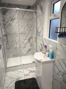 a white bathroom with a shower and a sink at Edlin Guest House in Reading