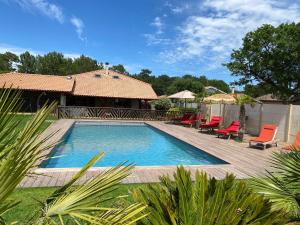 a swimming pool in a yard with chairs and a house at Villa Valhalla - 400m from beach, sauna and big heated pool in Labenne